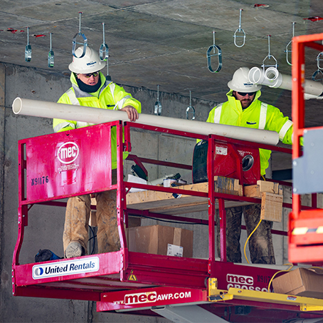 Two construction workers installing plumbing